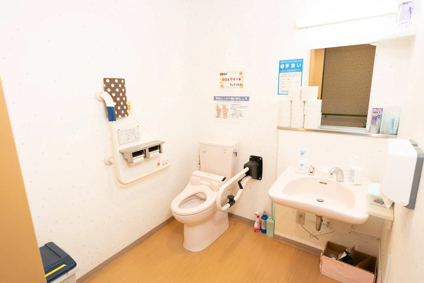 介護施設のトイレ・洗面エリア。温便座、手すり、洗面台が備わっている。